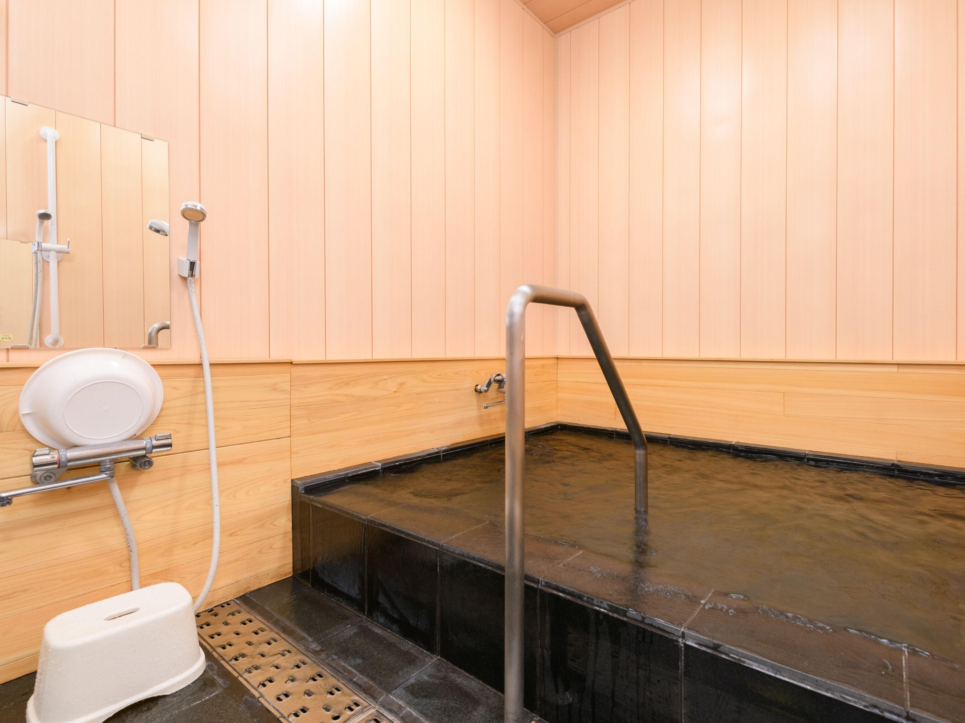 A sauna room with a black heated floor, a white heater, and a white toilet.