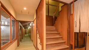 Un interior japonés tradicional con una escalera de madera, suelo de tatami y puertas correderas.