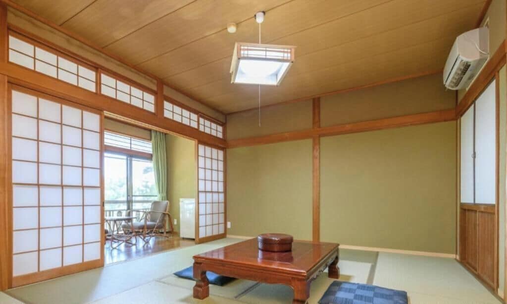 Una habitación japonesa tradicional con suelo de tatami, una mesa de madera baja y puertas correderas.