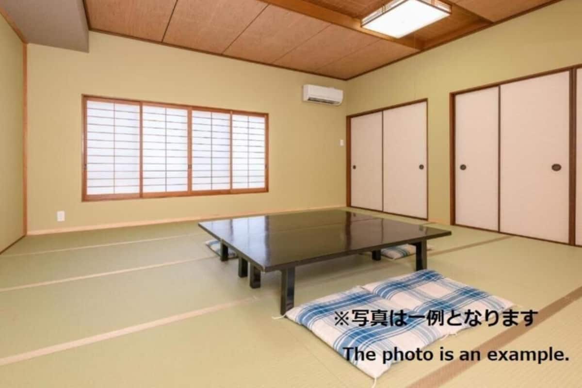 Una habitación japonesa tradicional con suelo de tatami, una mesa baja, puertas correderas y un divisor shoji.