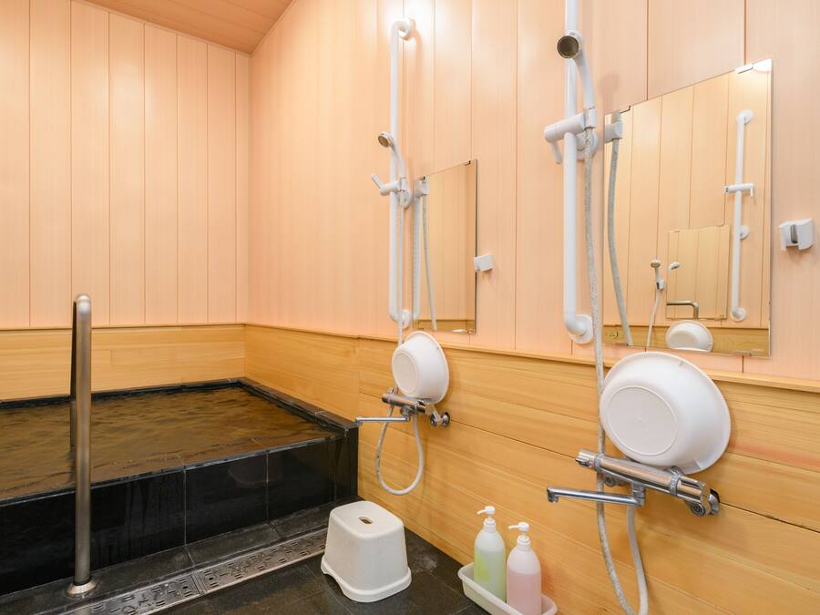 A wooden-paneled bathroom with a bathtub, a toilet, and a shower area.