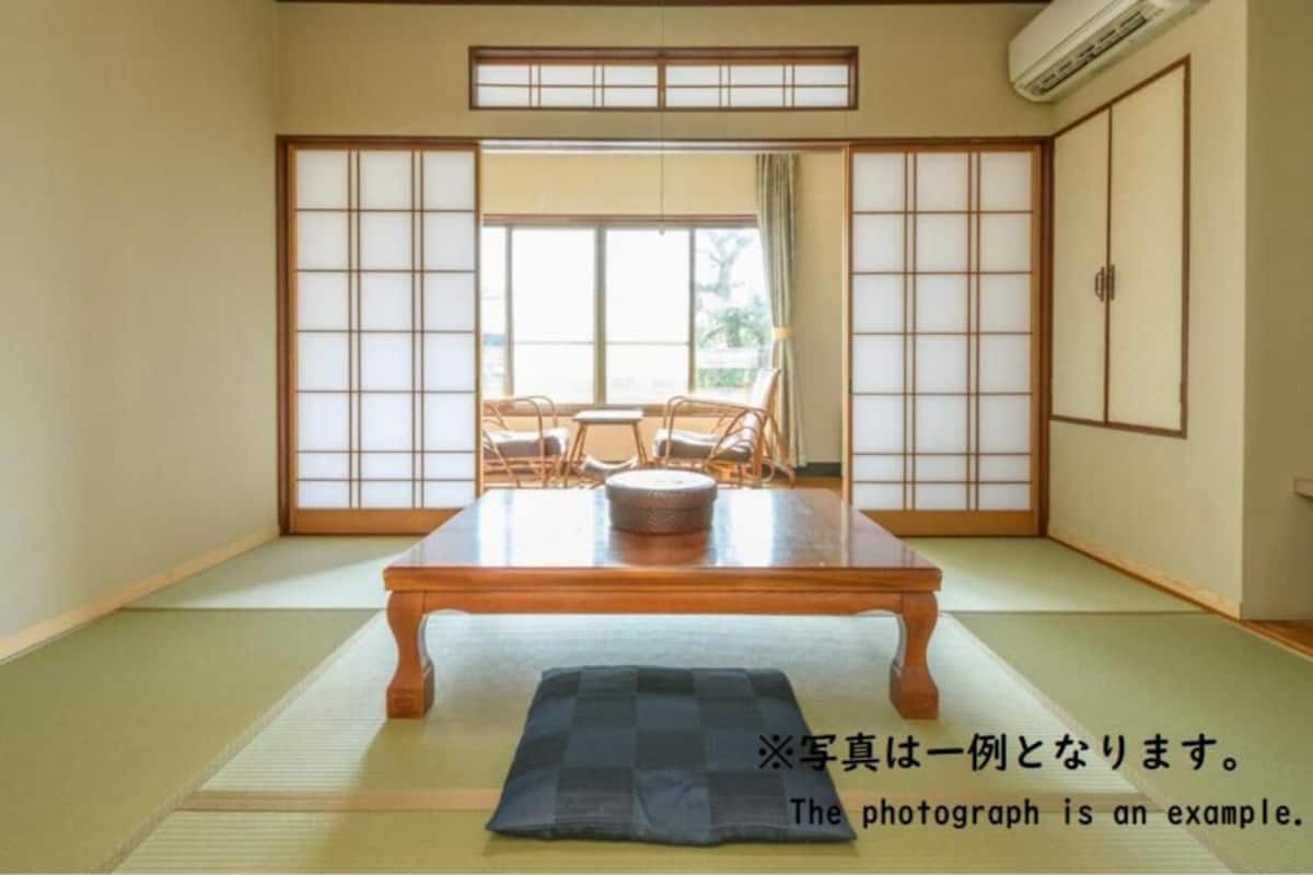 Una habitación japonesa tradicional con suelo de tatami, una mesa de madera baja y puertas correderas shoji.