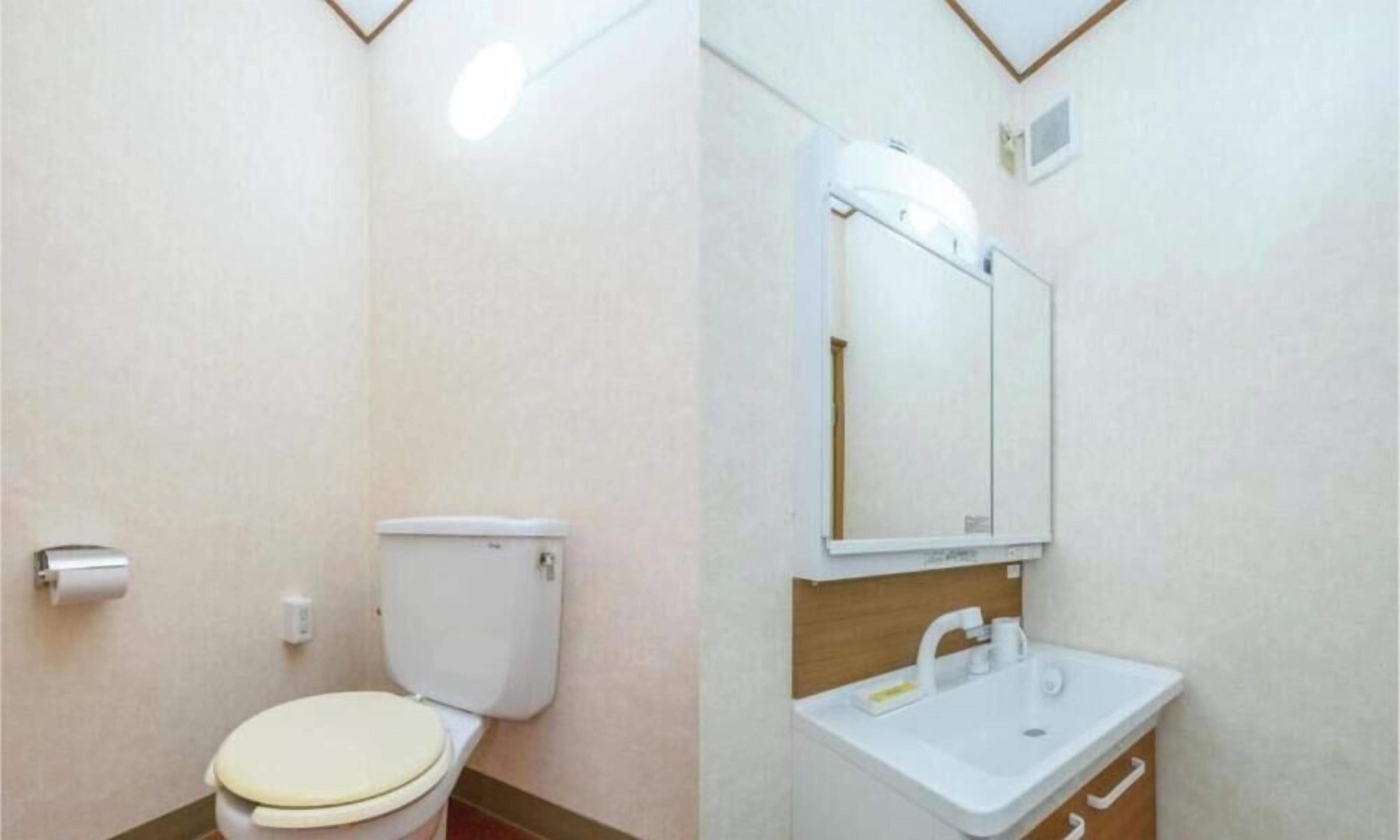 A bathroom with a toilet, sink, and mirror.