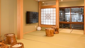 Una habitación japonesa tradicional con suelo de tatami, un panel shoji, un televisor y muebles de madera.