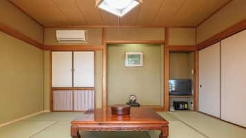 A traditional Japanese room with tatami flooring, a wooden table, sliding doors, and a television.