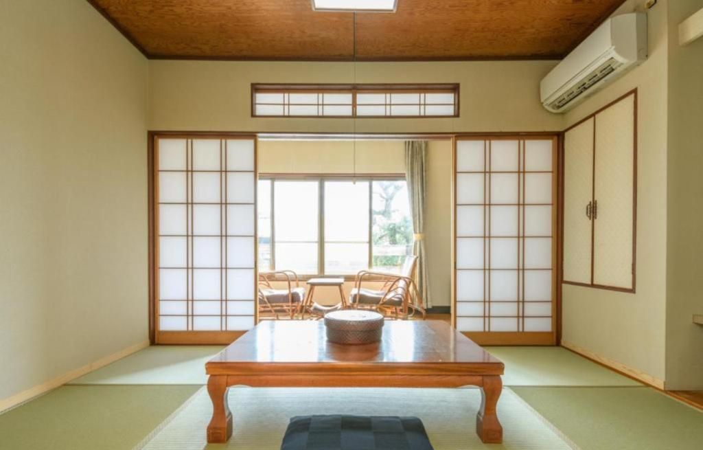 Um quarto japonês tradicional, com tatames, uma mesa de madeira baixa e portas deslizantes shoji.