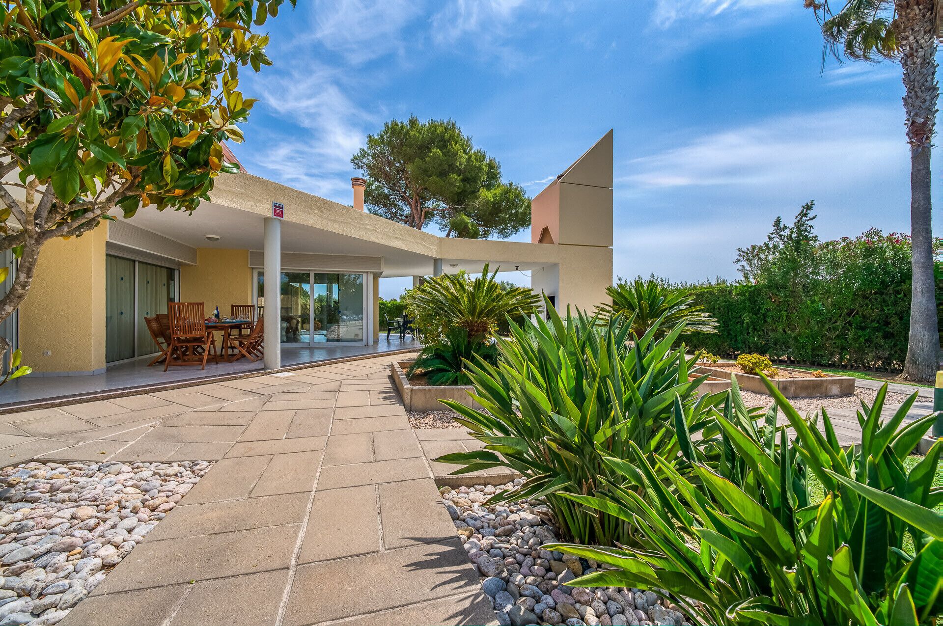 A modern house with a patio, outdoor seating, and a garden.
