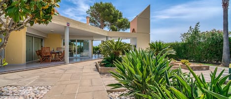 A modern house with a patio, outdoor seating, and a garden.