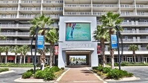 Ingresso di un hotel con un grande cartello con la scritta 'The Wharf' e un maxischermo pubblicitario che offre il '10% di sconto per nuovi clienti'.