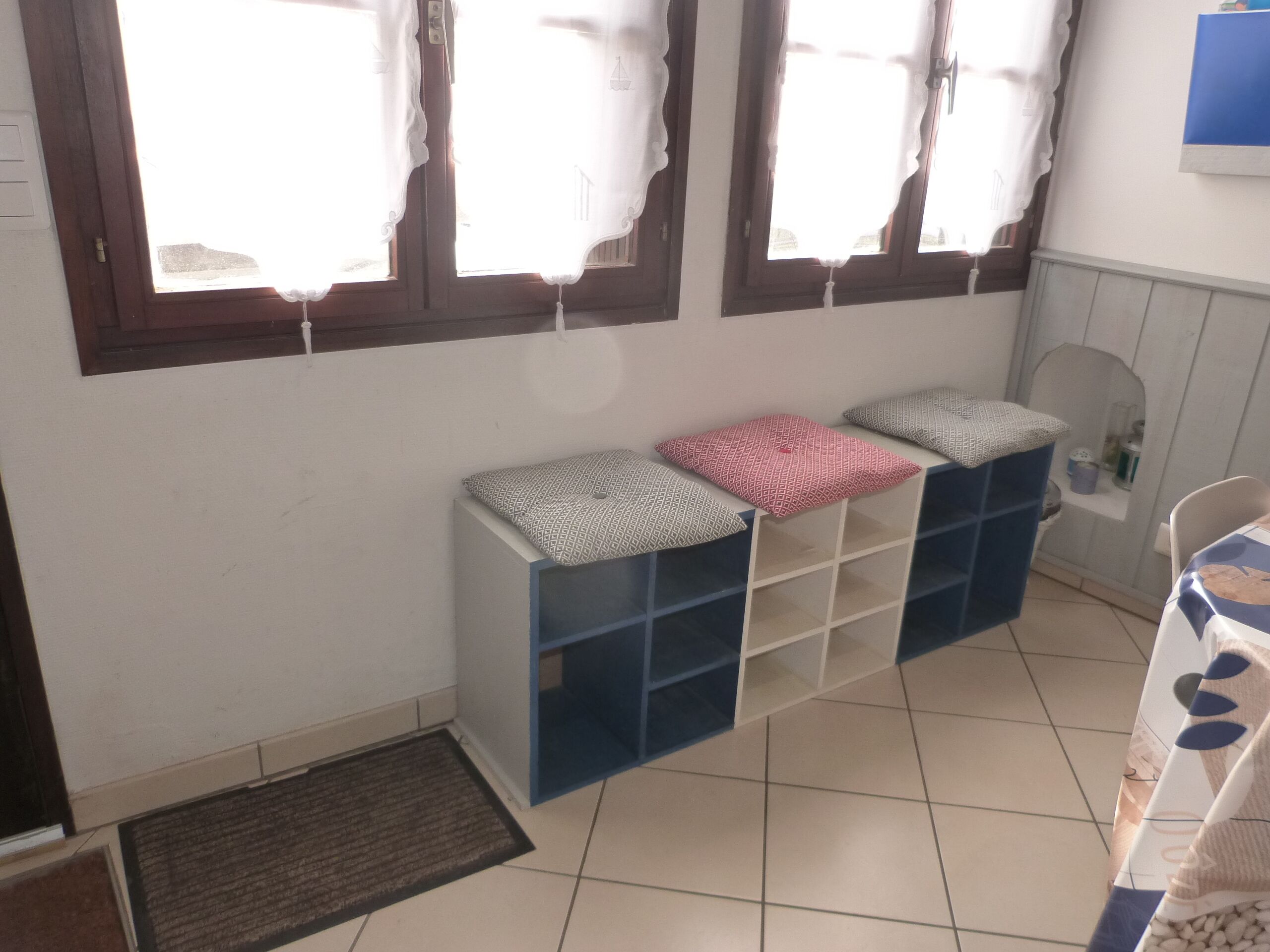 Een kamer met een bank, opbergladen, een tafeltje en een stoel.