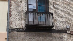 A two-story building with a brick facade, a balcony with a metal railing, and a door with a geometric pattern. - Atypical fisherman's house for 6 person and a baby (Dieppe)