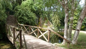 A wooden bridge with a metal railing over a small stream, surrounded by trees and greenery. - Atypical fisherman's house for 6 person and a baby (Dieppe)