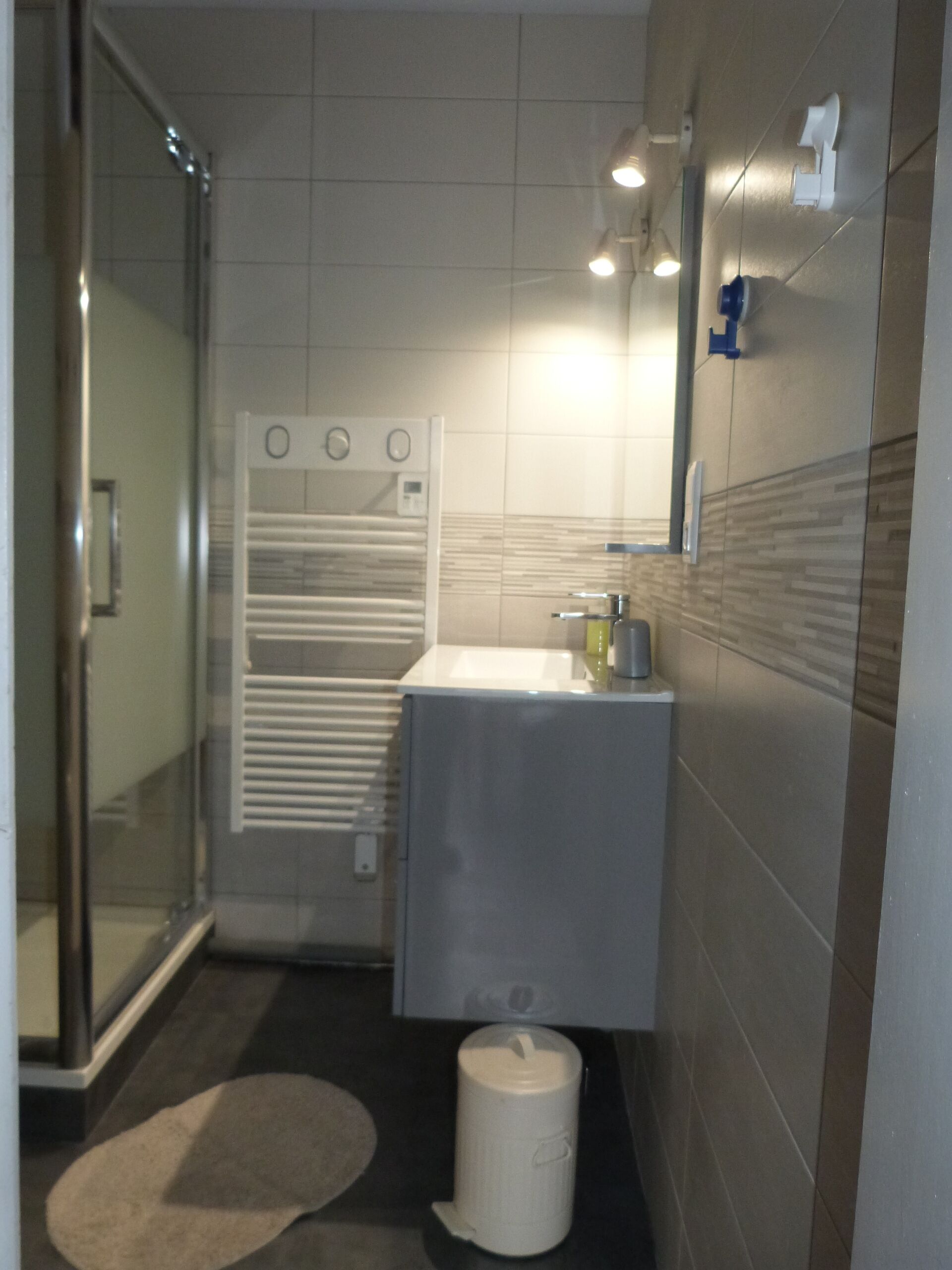 Een moderne badkamer met een glazen douchecabine, een wit wastafelmeubel en een toilet.