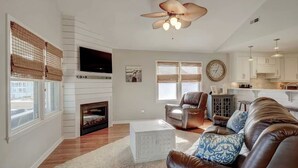 A living room with a fireplace, leather sofa, and a television. - 2 Blocks from Beach, Dog Friendly w/ no dog fees!, Hot Tub, Fenced Yard (Kure Beach)