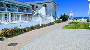 Un hôtel situé en bord de mer, doté d’une promenade dallée, d’un balcon avec des garde-corps et offrant une vue sur l’océan.