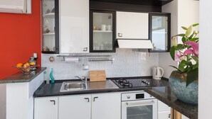 A modern kitchen with white cabinets, a black countertop, and a built-in oven. - Sea View Apartments - Apartment Merivo (Dubrovnik)