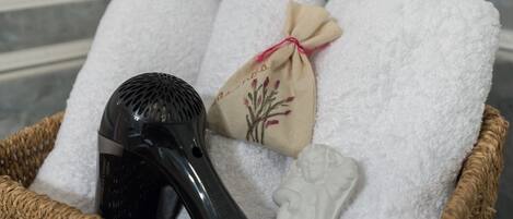 Manden met een haardroger, een opgevouwen handdoek, een klein waszakje en een witte beeldfiguur.