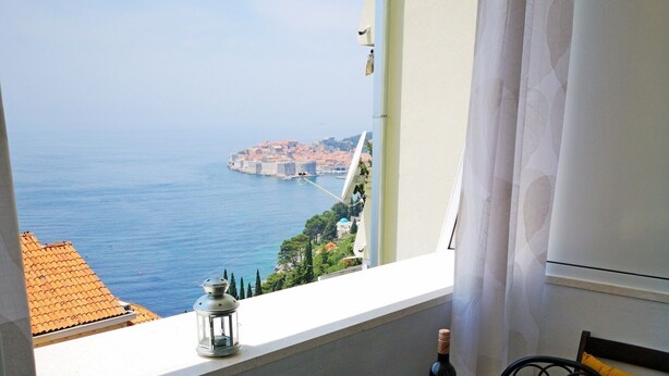 A balcony with a table, chairs, a bottle of wine, and a tray. - Sea View Apartments - Apartment Merivo (Dubrovnik)