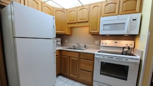 A kitchen with wooden cabinets, a white refrigerator, a microwave, a stove, and a sink. - LOWER LAST MINUTE WEEKDAY PRICE!! Come relax in Destin without the crowds! (Destin)