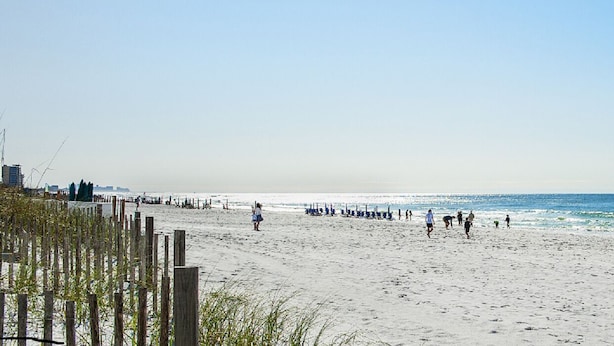 A beach with a wooden fence, beach chairs, and umbrellas. - LOWER LAST MINUTE WEEKDAY PRICE!! Come relax in Destin without the crowds! (Destin)