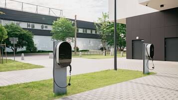 Two electric vehicle charging stations in an outdoor area with a modern building in the background.