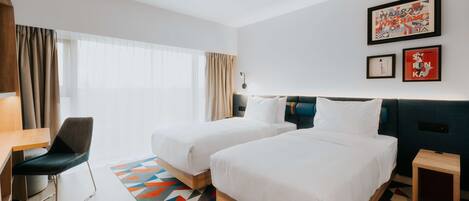 Una habitación de hotel con dos camas, un escritorio, una silla y una mesita.