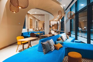A modern interior with blue seating, wooden tables, and a curved ceiling design. - (Warsaw)