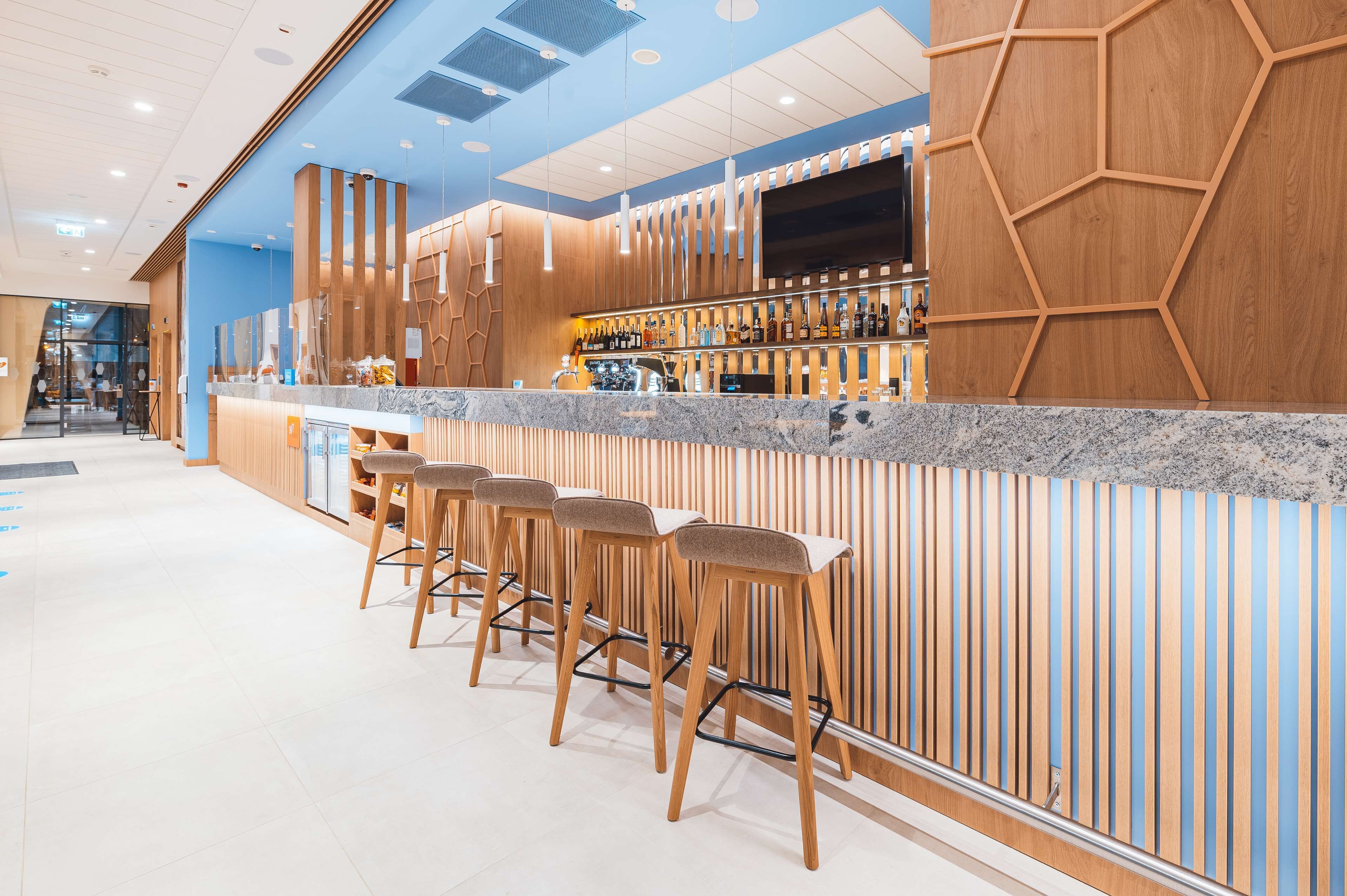 A modern bar area with wooden accents, bar stools, and a countertop.