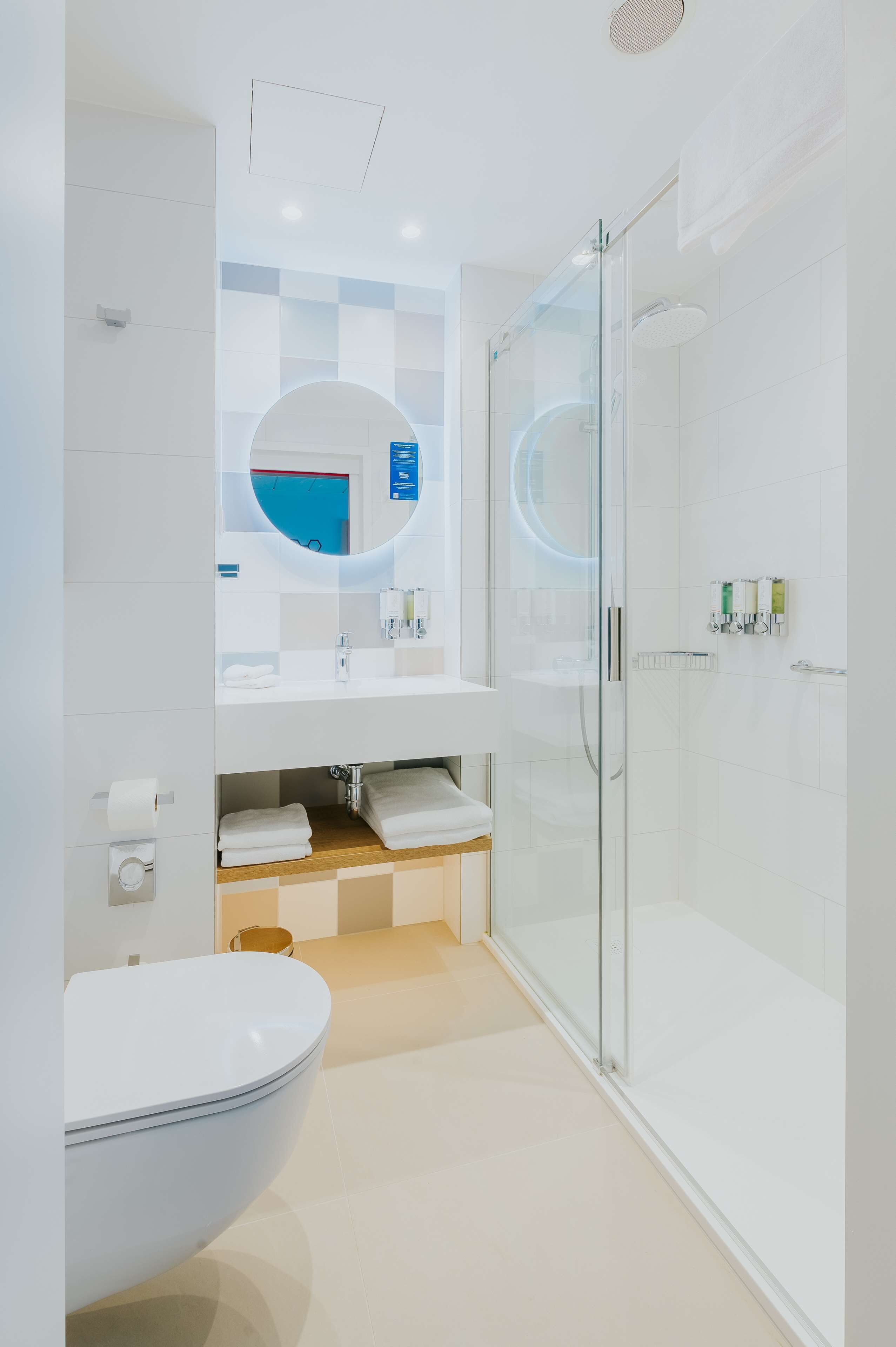 A modern bathroom with a toilet, sink, and glass-enclosed shower.