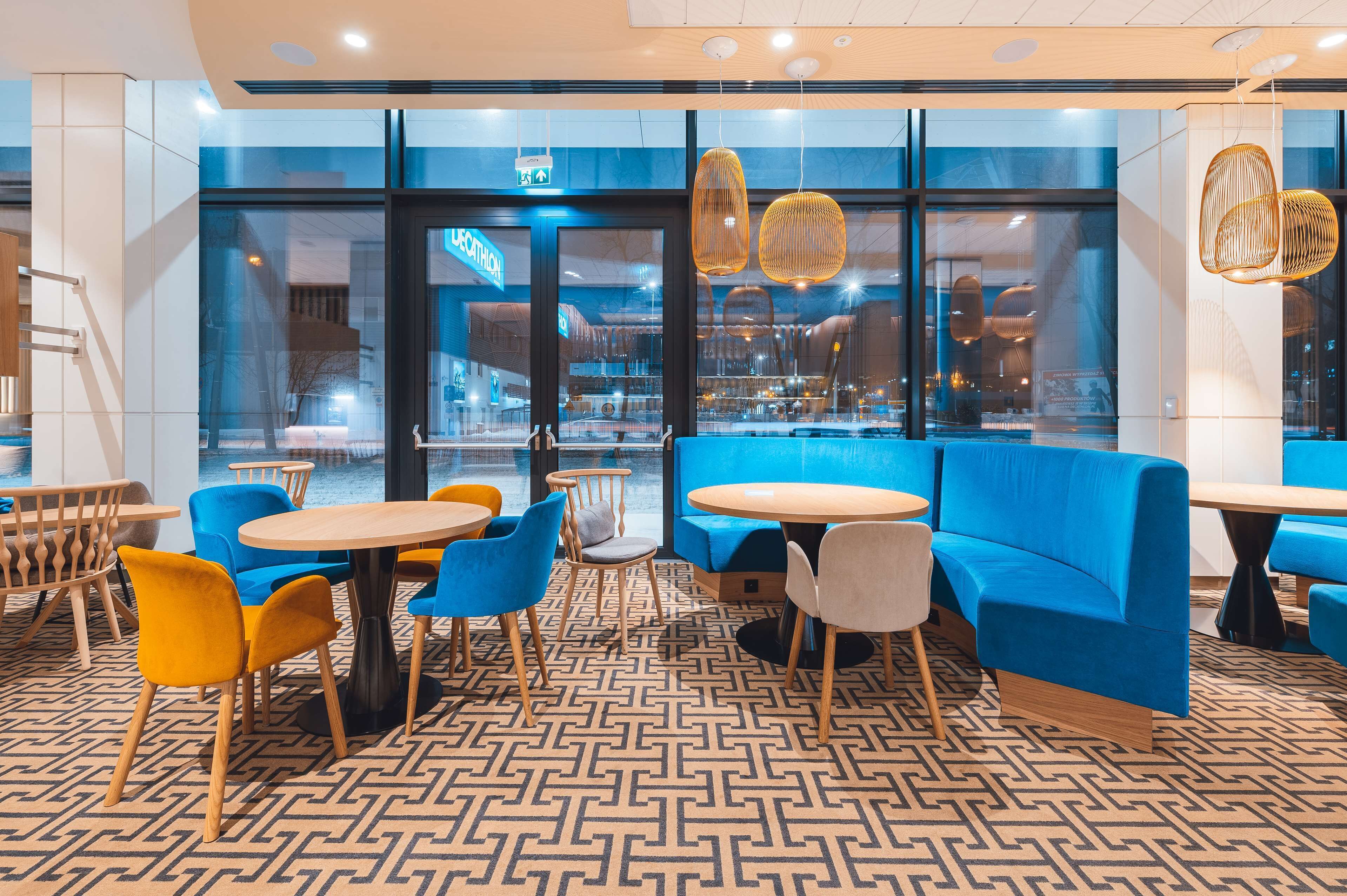 A modern interior with blue seating, wooden tables, and patterned flooring.