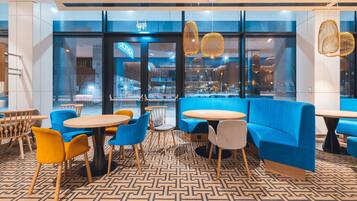 A modern interior with blue seating, wooden tables, and patterned flooring.