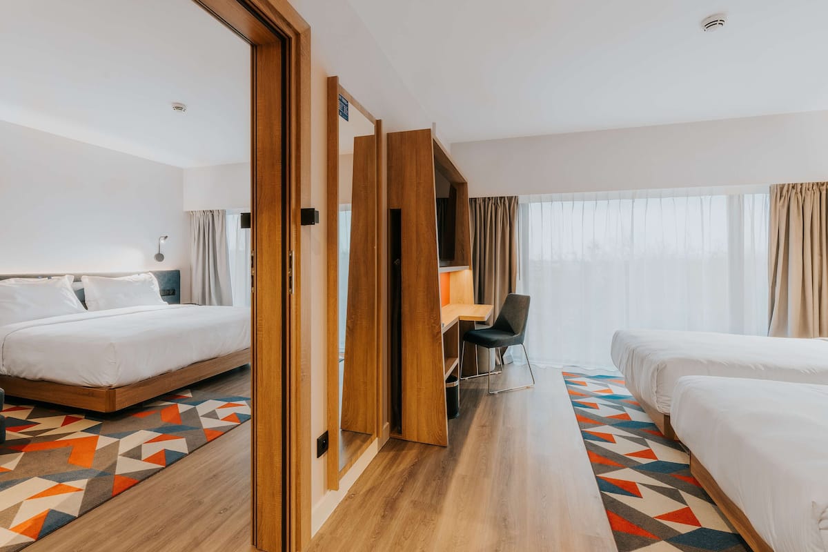 A hotel room with two beds, a desk, and a chair.
