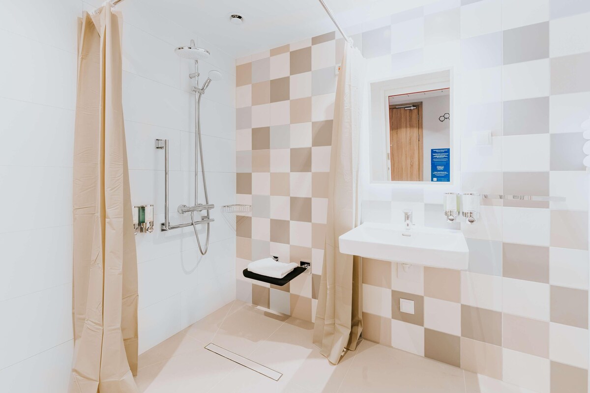 A modern bathroom with a shower, a sink, and a mirror.