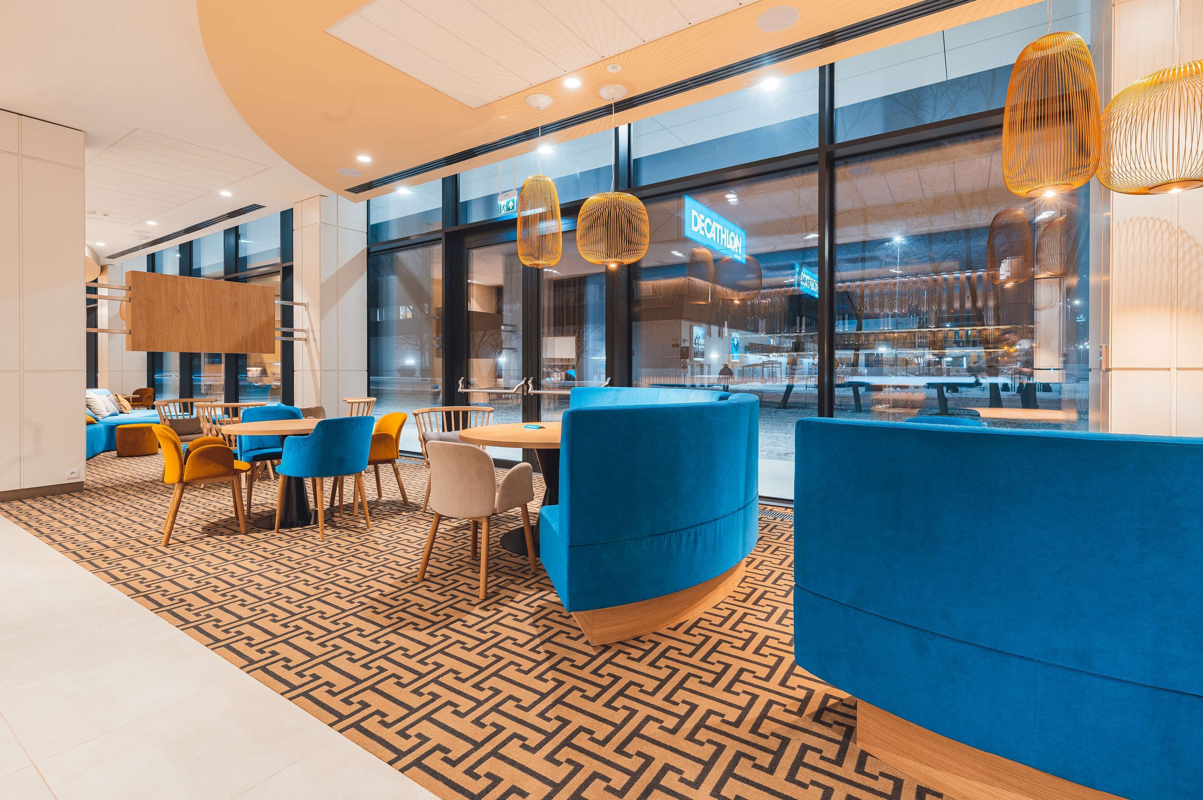 A modern restaurant with blue seating, wooden tables, and patterned flooring.