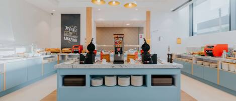 Une cuisine moderne dotée d’un îlot central, de meubles de couleur bleue et d’un mur décoré d’une citation inspirante.