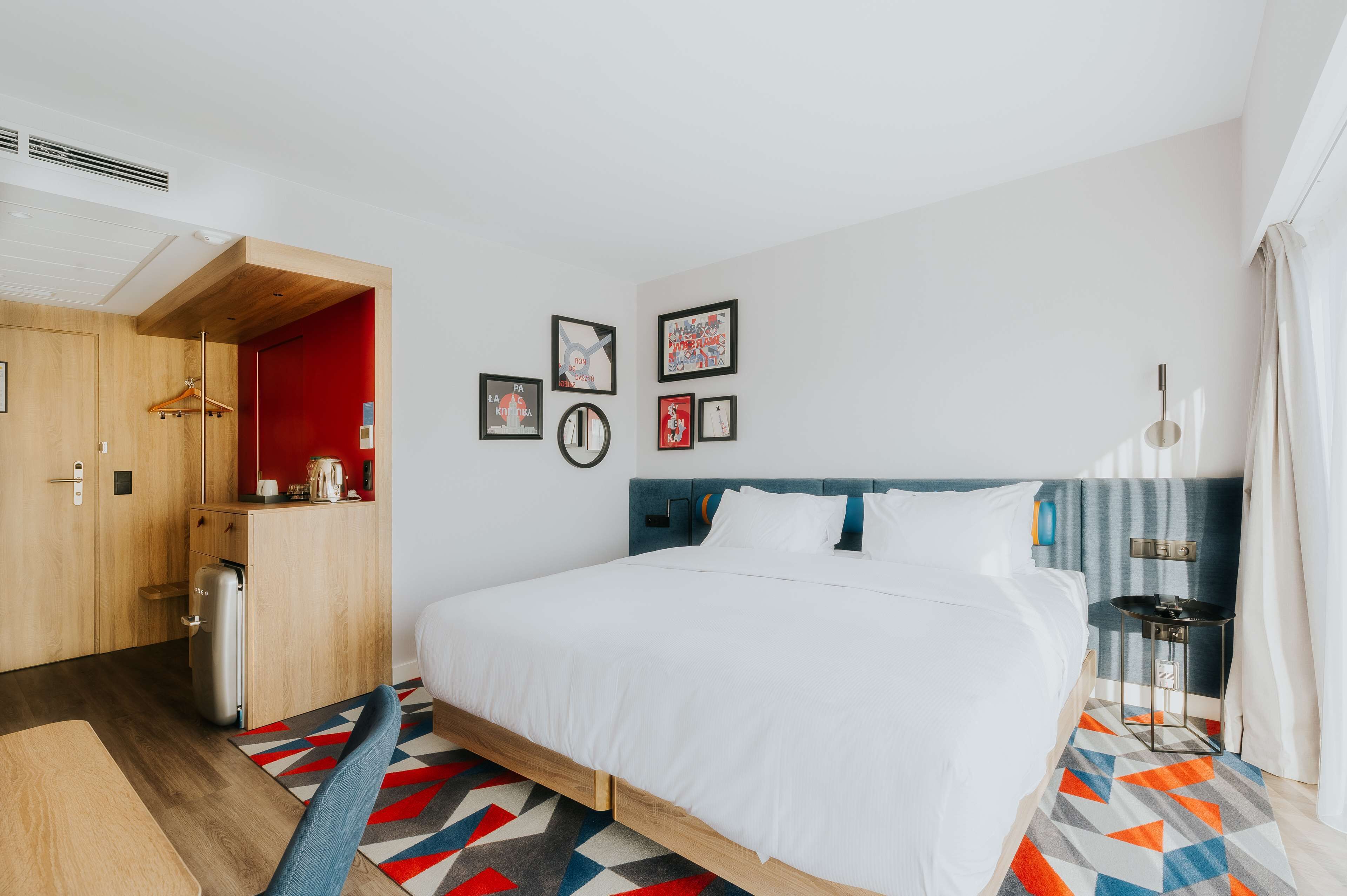Habitació d'hotel amb llit, taula petita, cadira, armari i bany.