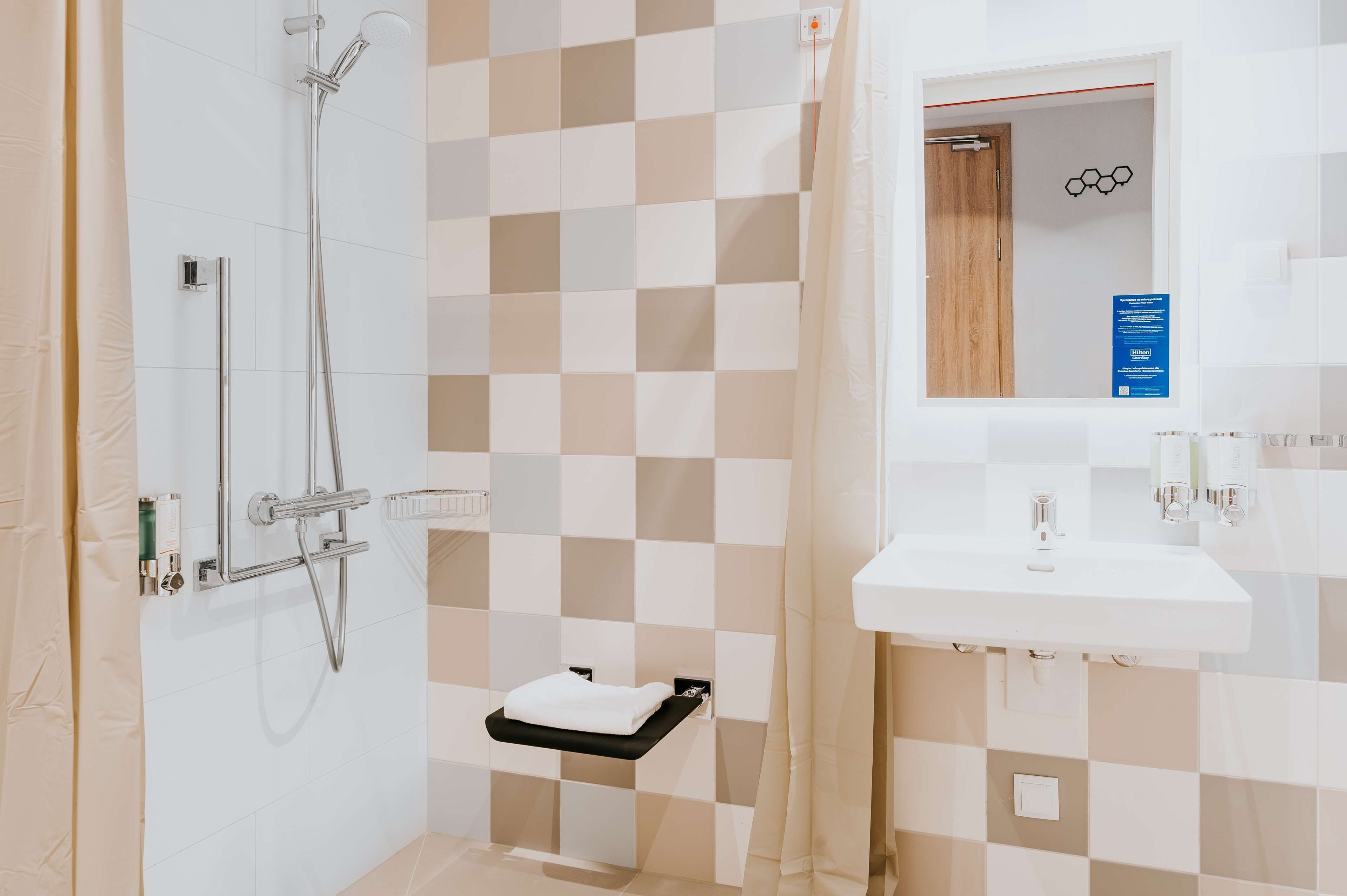 A modern bathroom with a shower, a sink, and a towel rack.