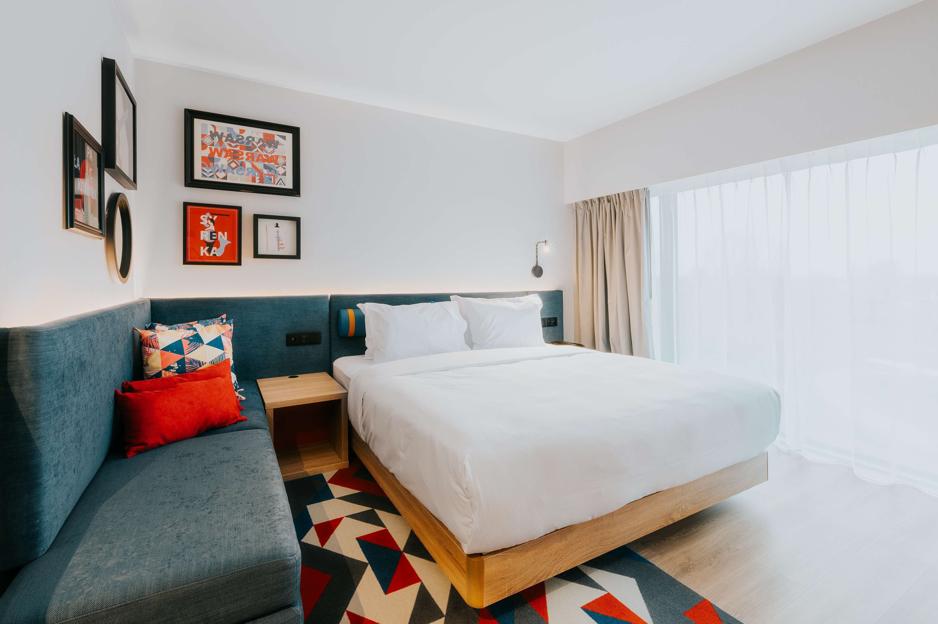 A modern hotel room with a bed, a sofa, and a nightstand.