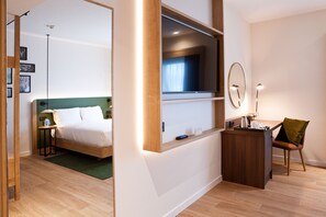 Ein modernes Hotelzimmer mit Bett, Schreibtisch, Fernseher und Spiegel.
