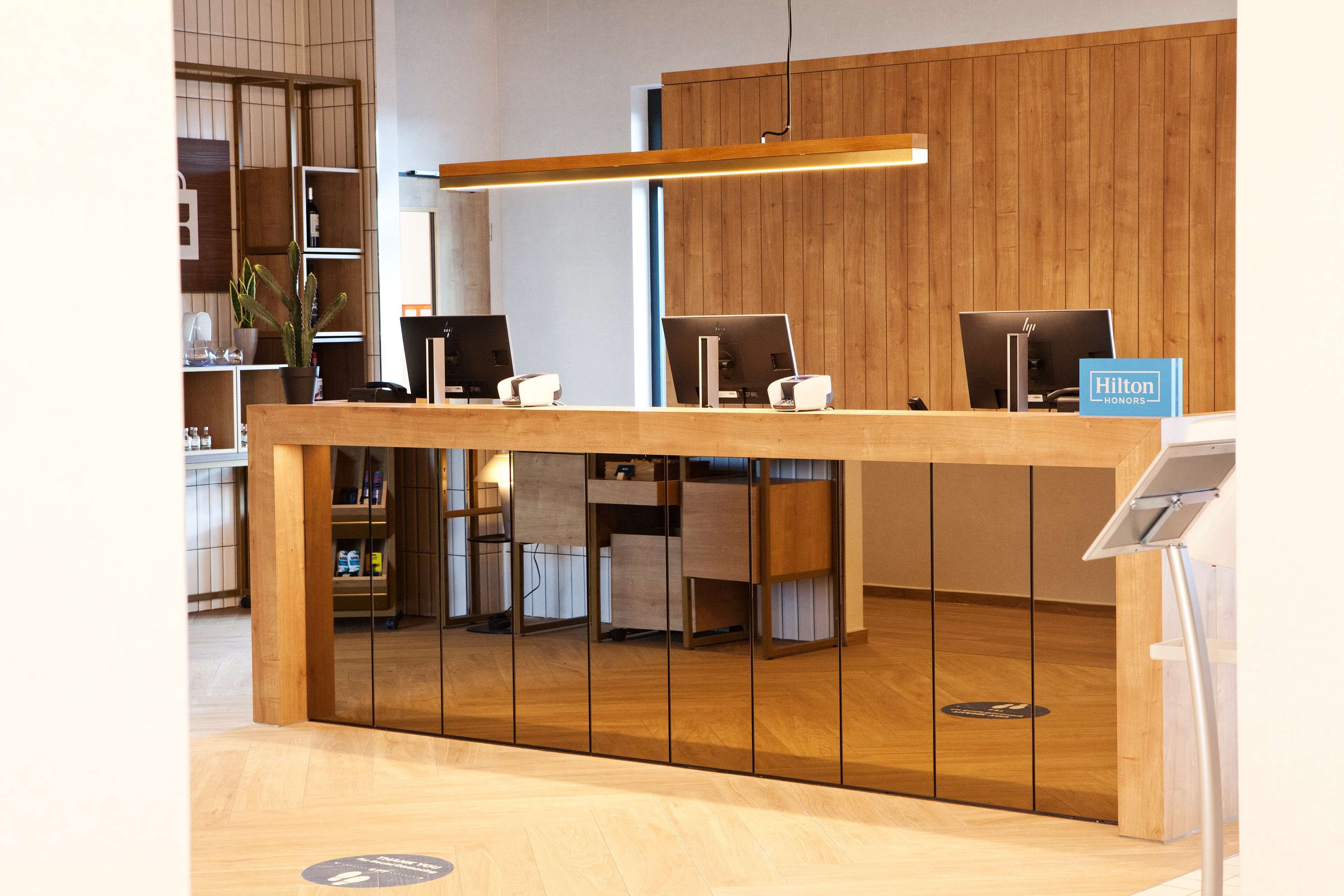 A reception desk with computers, a sign for Hilton Honors, and a wooden panel wall.