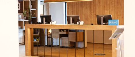 A reception desk with computers, a sign for Hilton Honors, and a wooden panel wall.