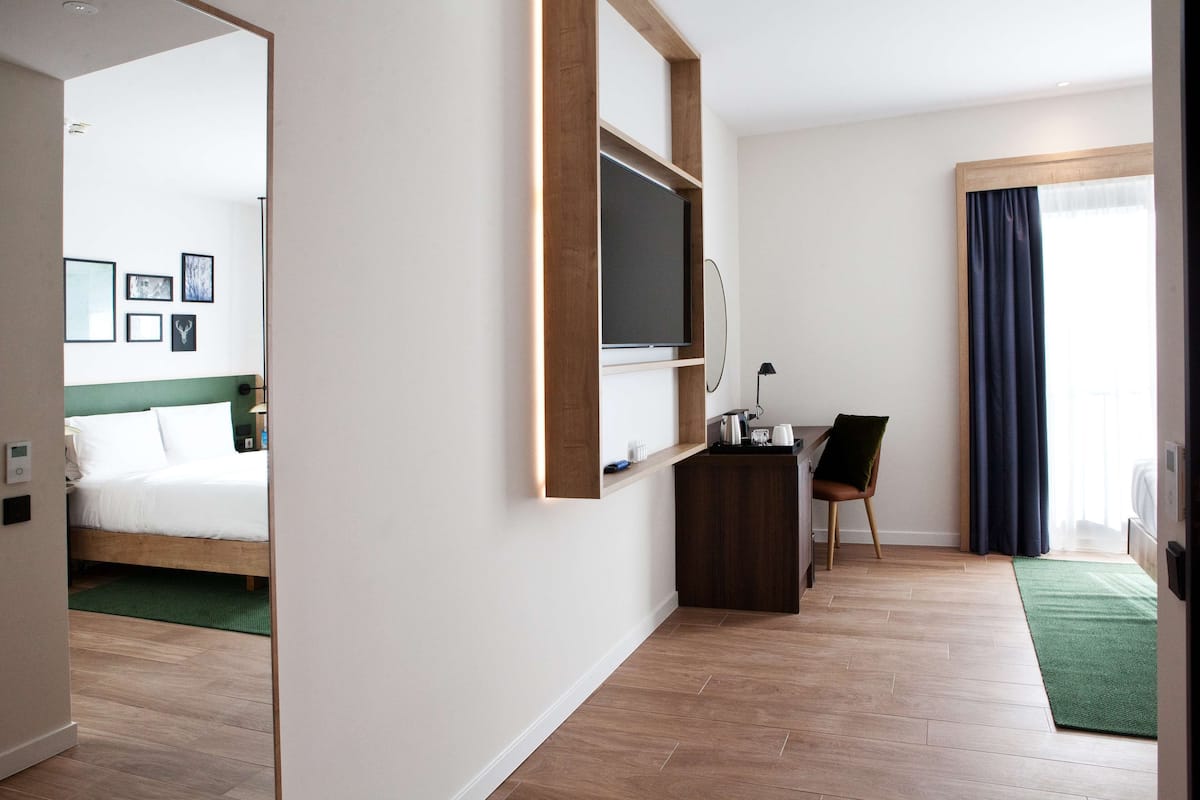 A hotel room with a bed, a desk, a chair, a television, and a window with curtains.