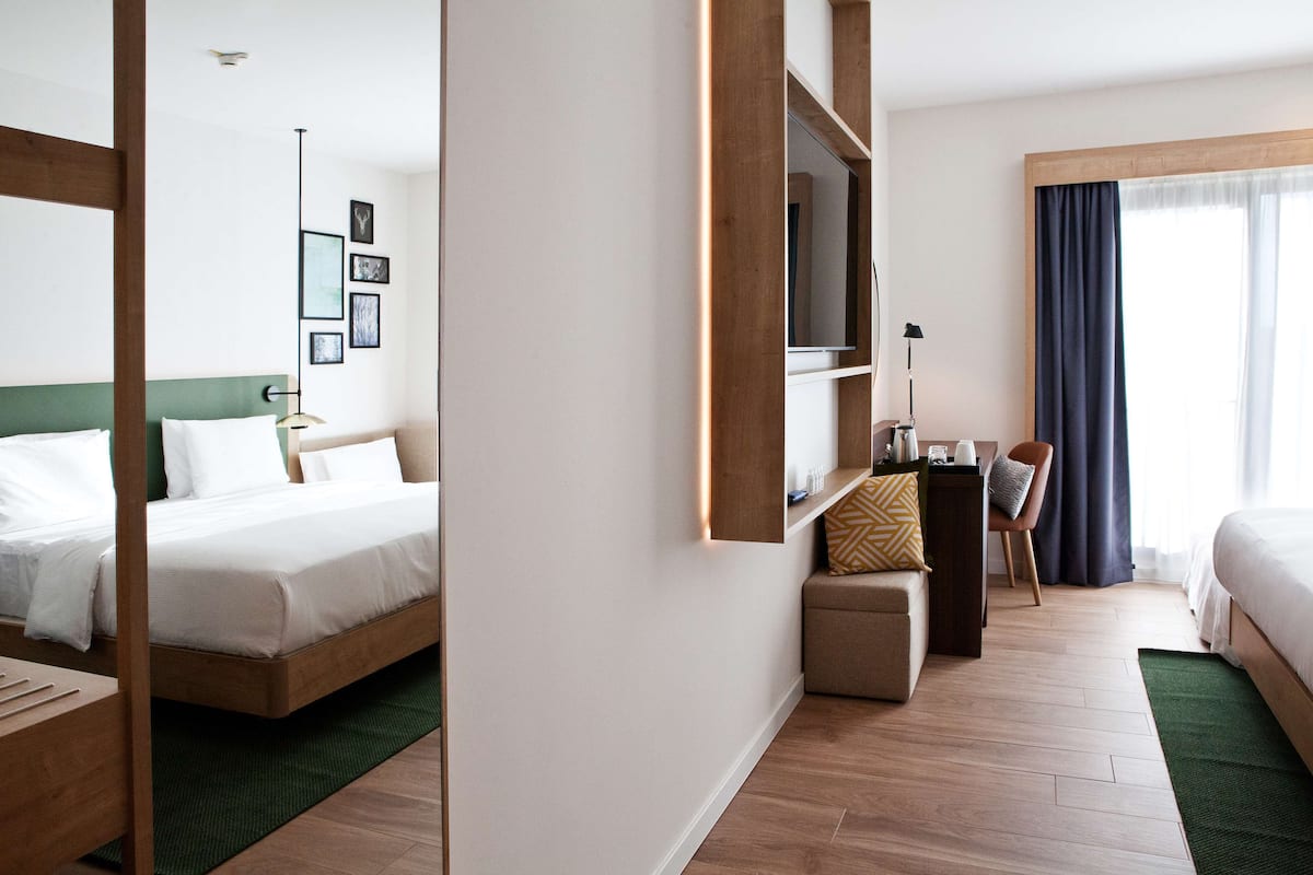A hotel room with a bed, a desk, a chair, and a TV.