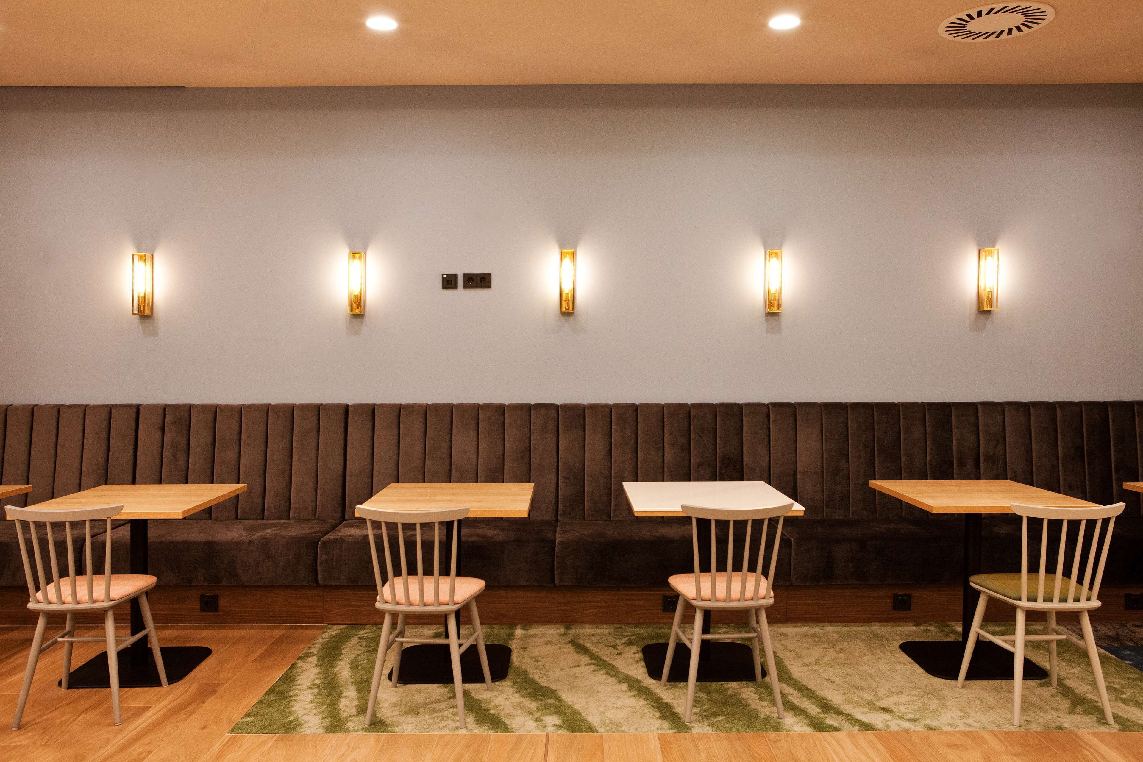 A seating area with a brown cushioned bench, wooden tables, and chairs.