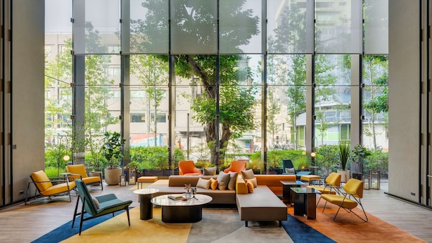A spacious indoor area with large windows, modern furniture, and a variety of plants. - Hotel Resonance Taipei, Tapestry Collection by Hilton (Taipei)