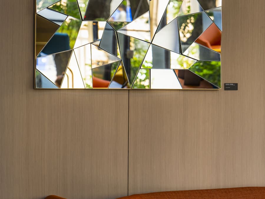A modern interior with a geometric wall art piece and a contemporary orange sofa.