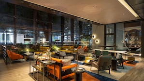A modern interior with large windows, a mix of seating areas, and a dining space. - Hotel Resonance Taipei, Tapestry Collection by Hilton (Taipei)