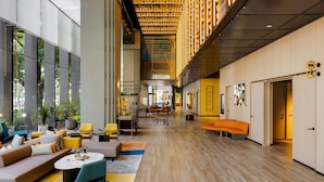A spacious lobby with a high ceiling, wooden paneling, and a central seating area with sofas and chairs. - Hotel Resonance Taipei, Tapestry Collection by Hilton (Taipei)