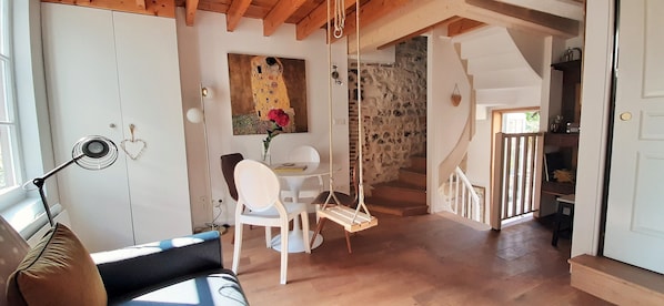 Cozy interior space with a dining area, staircase, and exposed wooden ceiling.