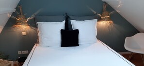 Cozy retreat with a comfortable bed, white chair, and wall-mounted lamps.